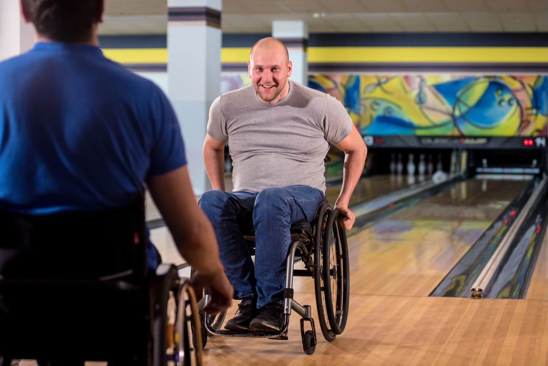 Two disabled friends in wheelchairs bowling