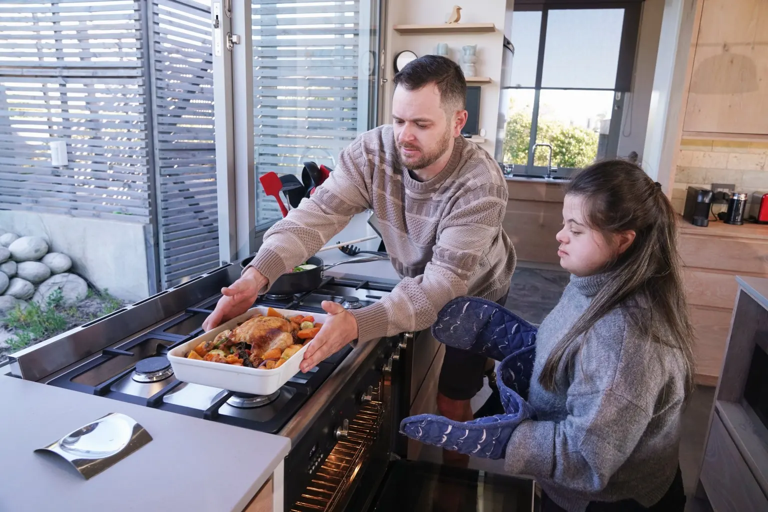 Support worker in disabled woman with down syndrome cooking in kitchen