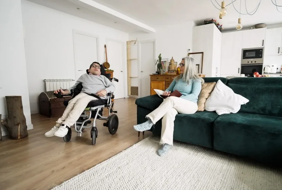 Disabled man in wheelchair with support worker at home